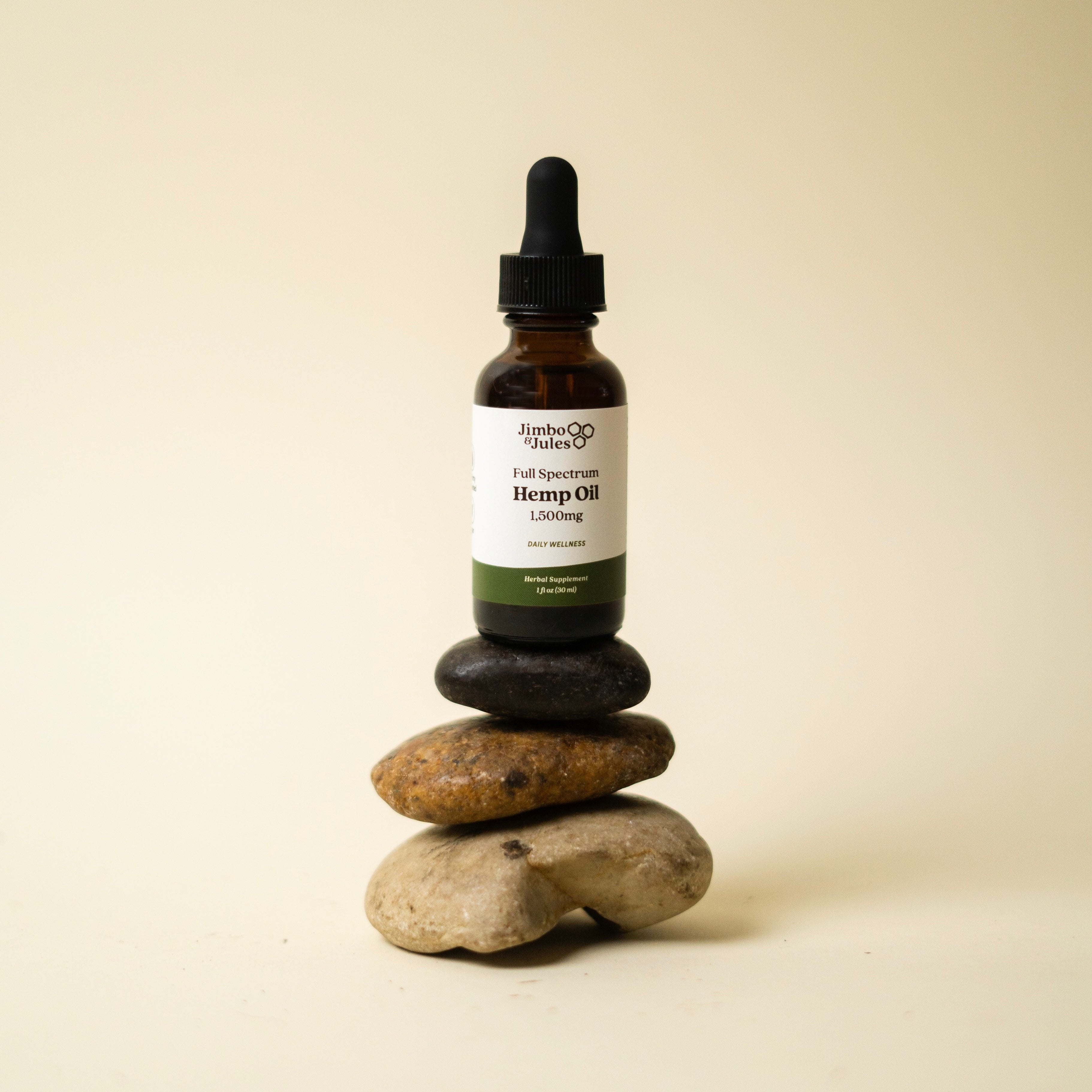 Jimbo & Jules full spectrum hemp oil bottle sitting on top of three rocks